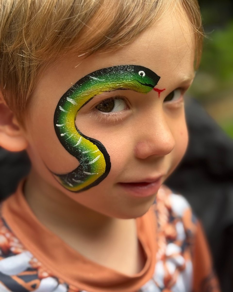 Child with green and yellow snake face painting by Wildflower Face Art